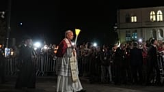 Pope Leo XIV holds a candle during a prayer of Holy Rosary and torchlight procession at the Sanctuary of Our Lady of Lourdes.