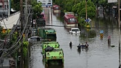 People wade through a flooded street after heavy rain in Bangkok.