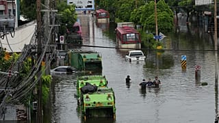 People wade through a flooded street after heavy rain in Bangkok.