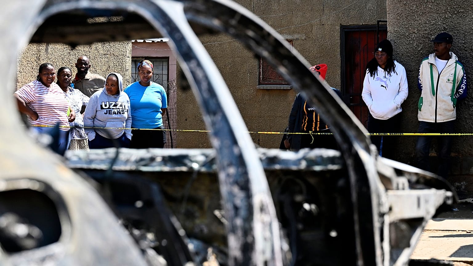 Community members stand at scene of a mass shooting at a bar in Wedela township, 27 September, 2026