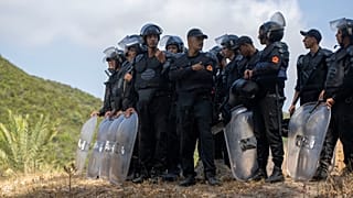 Las fuerzas de seguridad marroquíes montan guardia mientras los migrantes se reúnen en una colina en Fnideq, el 15 de agosto de 2026.
