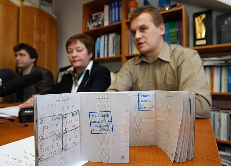 Mikhas Yanchuk, a journalist of the Belsat channel, right, show his passport with a stamp that bans him leaving the country, in Minsk, Belarus, Thursday 15 March, 2012