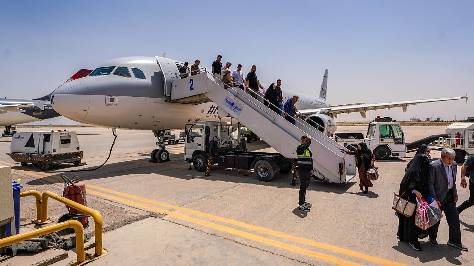 ركاب ينزلون من طائرة إيرانية في مطار النجف بعد انتهاء تعليق الرحلات الجوية الذي نجم عن الحرب الإقليمية التي اندلعت عقب ضربات أمريكية وإسرائيلية استهدفت إيران، وذلك في مدينة ال