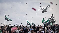 مروحية عسكرية تنثر الزهور وقصاصات الورق فوق حشود بإدلب احتفالاً بالذكرى الـ10 لانتصار المعارضة على قوات الأسد، 28 مارس 2025.