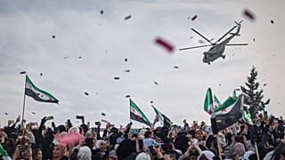 مروحية عسكرية تنثر الزهور وقصاصات الورق فوق حشود بإدلب احتفالاً بالذكرى الـ10 لانتصار المعارضة على قوات الأسد، 28 مارس 2025.