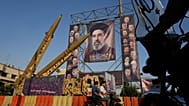 موتورسواران در کنار موشک‌های ایرانی و تصاویر رهبر ایران و فرماندهان و دانشمندان کشته‌شده در حملات اسرائیل و آمریکا، در جریان یک نمایشگاه نظامی در میدان بهارستان تهران.