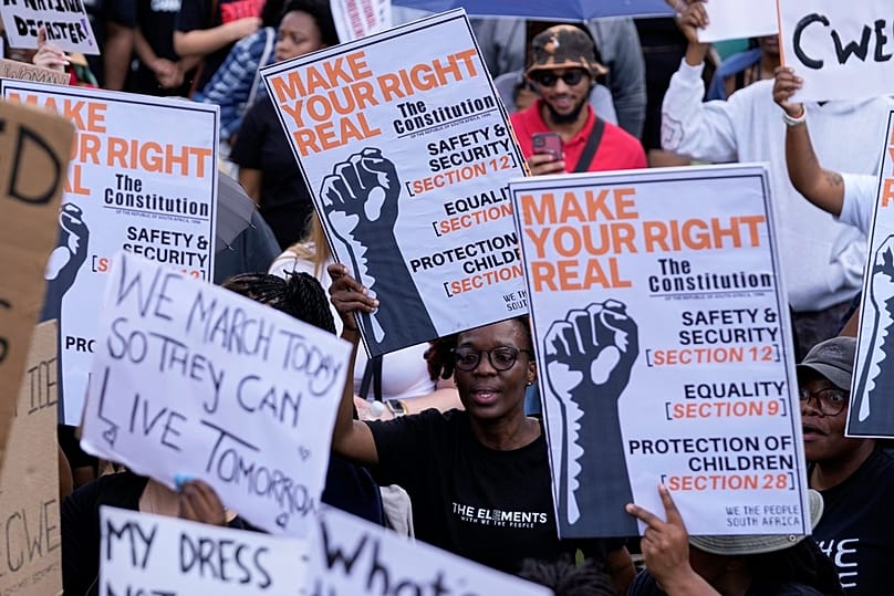 Activists hold placards during the women's protest at the Union Buildings in Pretoria, South Africa, Friday, April 11, 2025.