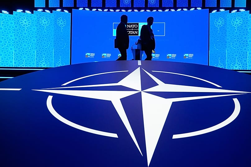 Two men walk past the NATO logo during the Defence Industry Forum at the NATO summit in Ankara, 7 July, 2026