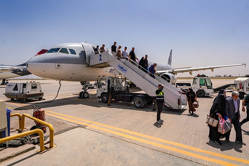 ركاب يغادرون طائرة إيرانية في مطار النجف بالعراق، 8 أيار 2026.