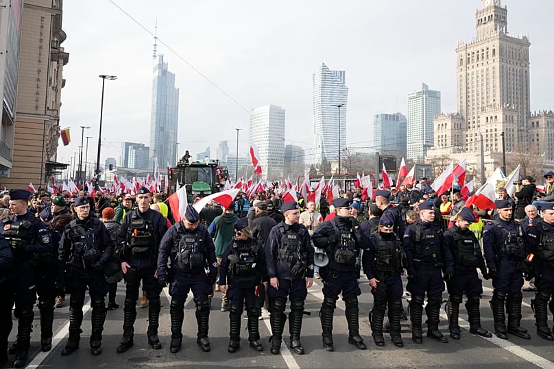 Polscy rolnicy z flagami narodowymi i tablicami z hasłami wyrażającymi sprzeciw protestują w Warszawie przeciwko unijnej polityce klimatycznej, 27 lutego 2024 roku.