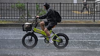 Un ciclista pedalea bajo un fuerte aguacero repentino en Tokio, jueves 13 de agosto de 2026.