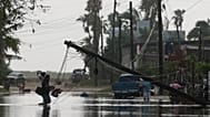Un hombre transporta objetos a través de aguas inundadas, pasando junto a líneas eléctricas derribadas tras el paso de Polo, el 29 de septiembre de 2026. 
