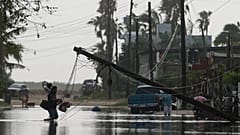 Un hombre transporta objetos a través de aguas inundadas, pasando junto a líneas eléctricas derribadas tras el paso de Polo, el 29 de septiembre de 2026. 