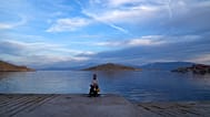 A woman sits at the port of the tiny Aegean island of Chalki, southeastern Greece, Friday, Nov. 5, 2021