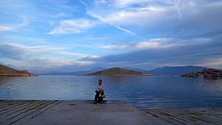 A woman sits at the port of the tiny Aegean island of Chalki, southeastern Greece, Friday, Nov. 5, 2021