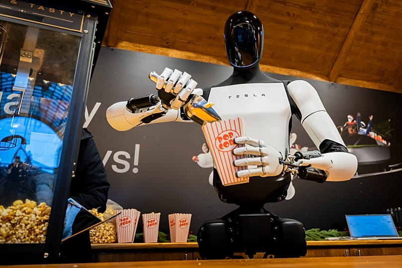 ARCHIVO. El robot humanoide Optimus, de Tesla, reparte palomitas en un puesto de un mercado navideño durante su presentación en un centro comercial de Berlín, Alemania, 20 de diciembre de 2025