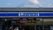 Menschen kaufen in einem Laden in Fujikawaguchiko ein, dahinter ragt der Fuji auf, rund 110 Kilometer westlich von Tokio, am Freitag, 14. Juni 2024.