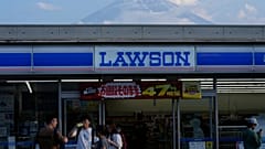People shop at a convenience store as Mount Fuji is seen behind the store in Fujikawaguchiko town, about 110 kilometers (68 miles) west of Tokyo, Friday, June 14, 2024.