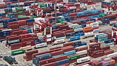 Trucks move past containers stored at a container terminal