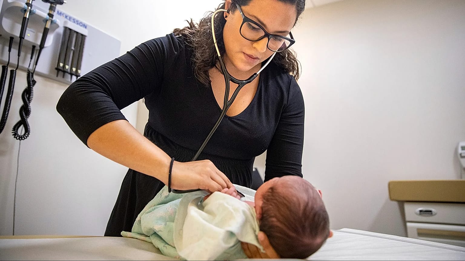 Una mujer ausculta a un niño recién nacido en México