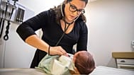Una mujer ausculta a un niño recién nacido en México