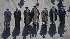 رجال دين شيعة يحملون بنادق يسيرون خلال عرض عسكري الطابع نظمته الدولة تحت شعار "جانفادا" (أو "التضحية من أجل إيران") في ساحة الثورة بطهران، إيران، يوم الجمعة 18 سبتمبر 2026. (ص