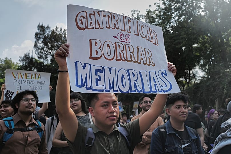 Un mexicano sostiene un cartel en el que se lee "Gentrificar es borrar memorias". 