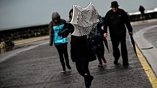 ARCHIVO: Una mujer intenta protegerse de la lluvia y del fuerte viento con su paraguas en España, en febrero de 2017.