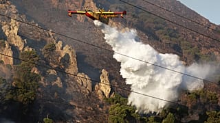 A firefighting plane drains water on a wildfire on the mountain in Altofonte near Palermo, 26 July, 2023