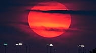 The sun sets beyond the lights of a distant youth baseball complex Sunday, Sept. 27, 2026, in Lenexa, Kan. (AP Photo/Charlie Riedel)