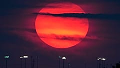 The sun sets beyond the lights of a distant youth baseball complex Sunday, Sept. 27, 2026, in Lenexa, Kan. (AP Photo/Charlie Riedel)