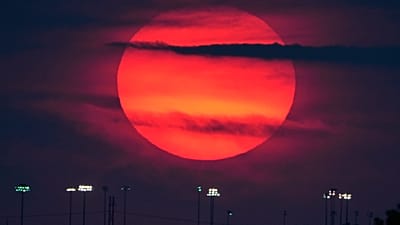 Die Sonne geht hinter den Flutlichtern eines entfernten Jugend-Baseball-Komplexes in Lenexa, Kansas, am Sonntag, 27. September 2026, unter. (AP Photo/Charlie Riedel)
