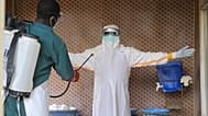 A healthcare worker in protective clothing is disinfected by a colleague inside a treatment center for Ebola patients in Beni, DR Congo.
