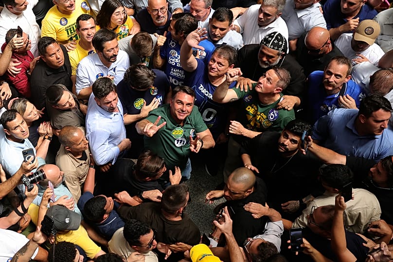 Opposition presidential candidate Sen. Flavio Bolsonaro, center, wearing a green shirt and looking up, campaigns in Sao Paulo, Brazil, Monday, 28 September2026.