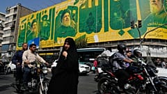 امرأة عند تقاطع طرق أمام لوحة إعلانية تعرض صوراً إحياءً للذكرى السنوية الثانية لمقتل حسن نصر الله، في طهران، إيران، يوم الأحد 27 سبتمبر 2026.