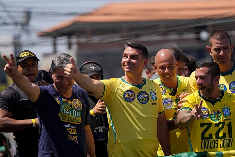 O candidato presidencial da oposição, o senador Flavio Bolsonaro, ao centro, faz um sinal de «polegar para cima» aos apoiantes durante um comício de campanha 