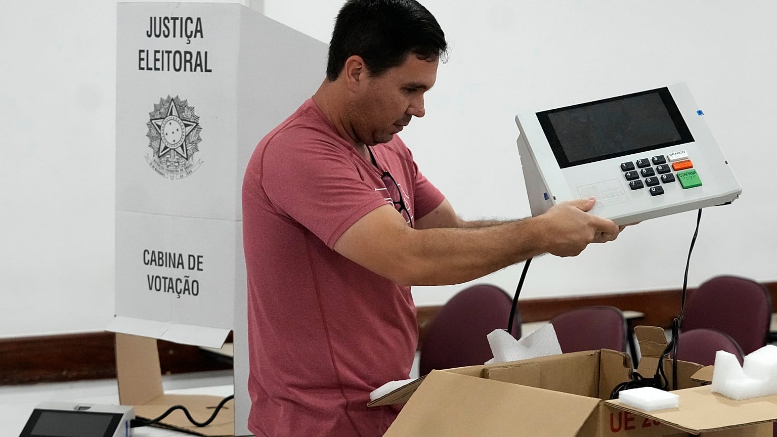Um coordenador de secção eleitoral segura uma máquina de votação eletrónica enquanto a prepara num centro de votação, na véspera das eleições gerais de domingo, em Brasília