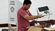 Um coordenador de secção eleitoral segura uma máquina de votação eletrónica enquanto a prepara num centro de votação, na véspera das eleições gerais de domingo, em Brasília