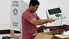 Un coordinador electoral sostiene una máquina de votación electrónica mientras la prepara en un centro de votación, en la víspera de las elecciones del domingo, en Brasilia