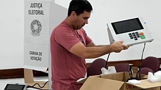 Um coordenador de secção eleitoral segura uma máquina de votação eletrónica enquanto a prepara num centro de votação, na véspera das eleições gerais de domingo, em Brasília