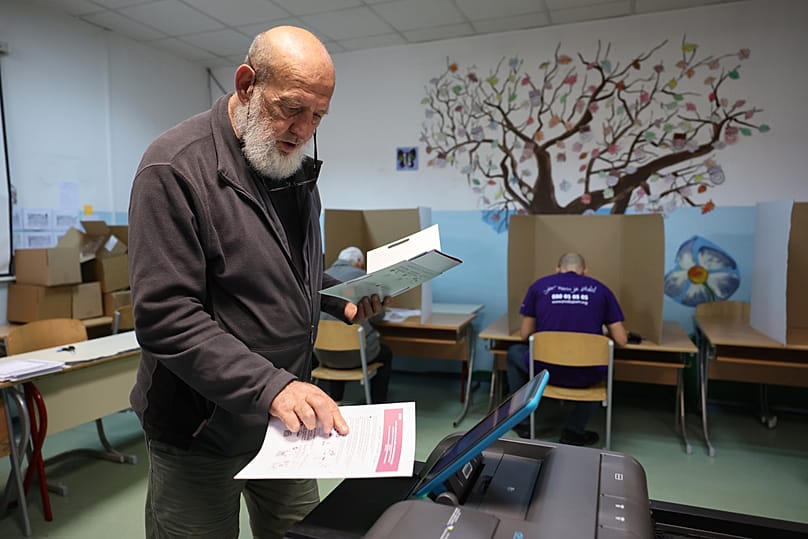 A man places his ballot into an electronic ballot box during the general election in Sarajevo, Bosnia, Sunday, Oct. 4, 2026
