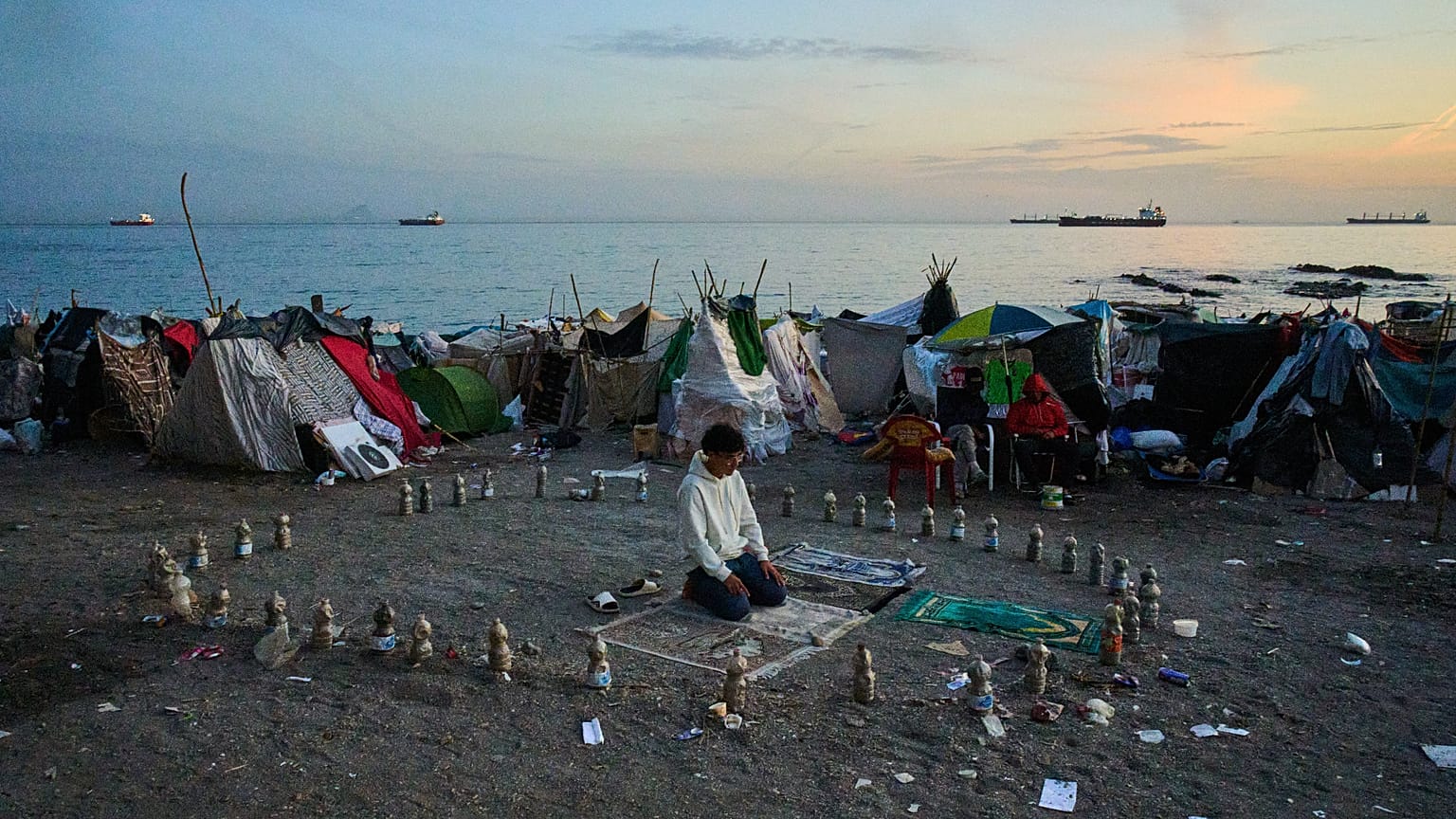 Migrante reza na manhã de quinta-feira, 1 de outubro de 2026, na praia de El Trampolín, no enclave espanhol de Ceuta