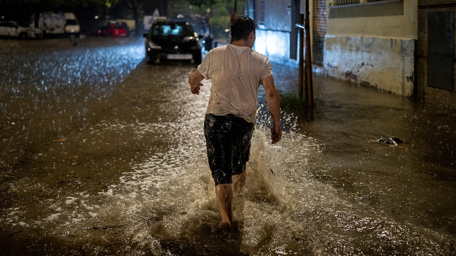 Un uomo cammina in una strada allagata durante un forte temporale a L'Hospitalet de Llobregat, alla periferia di Barcellona, in Spagna, domenica 4 ottobre 2026.