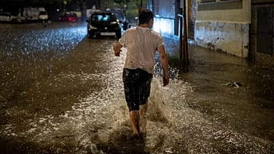 A man walks through a flooded street during heavy rain in L'Hospitalet de Llobregat, on the outskirts of Barcelona, Spain, Sunday, Oct. 4, 2026.