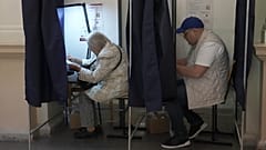 Eleitores preenchem boletins de voto nas legislativas numa assembleia de voto em Riga, na Letónia, sábado, 3 de outubro de 2026