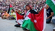 مشجع أردني بالكوفية والأعلام يتابع مباراة الأردن والأرجنتين بكأس العالم عبر شاشة عملاقة بالمدرج الروماني وسط عمّان، فجر الأحد 28 يونيو