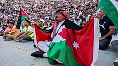 مشجع أردني بالكوفية والأعلام يتابع مباراة الأردن والأرجنتين بكأس العالم عبر شاشة عملاقة بالمدرج الروماني وسط عمّان، فجر الأحد 28 يونيو