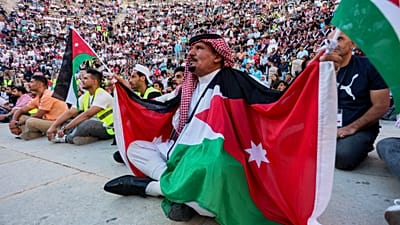 مشجع أردني بالكوفية والأعلام يتابع مباراة الأردن والأرجنتين بكأس العالم عبر شاشة عملاقة بالمدرج الروماني وسط عمّان، فجر الأحد 28 يونيو