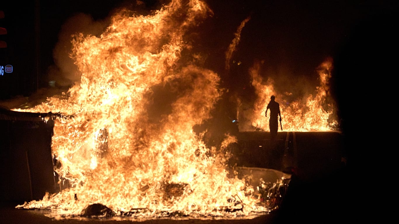 A demonstrator walks past burning rubbish bins after a protest over Spain's housing crisis, in Barcelona, Spain, on 5 October 2026.