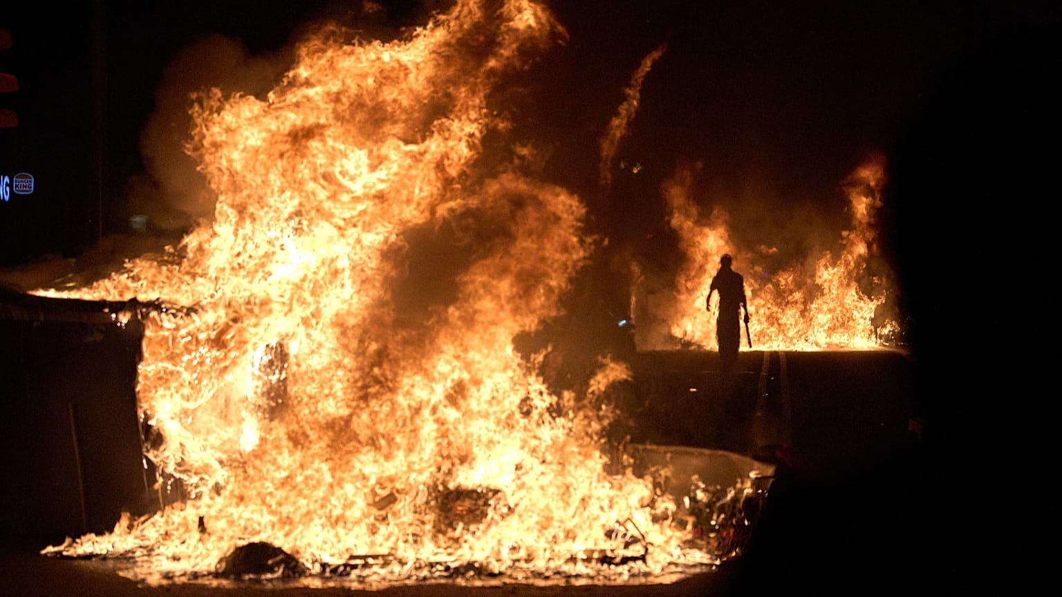 Un manifestante passa accanto a cassonetti dei rifiuti in fiamme dopo una protesta sulla crisi abitativa in Spagna, a Barcellona, il 5 ottobre 2026.